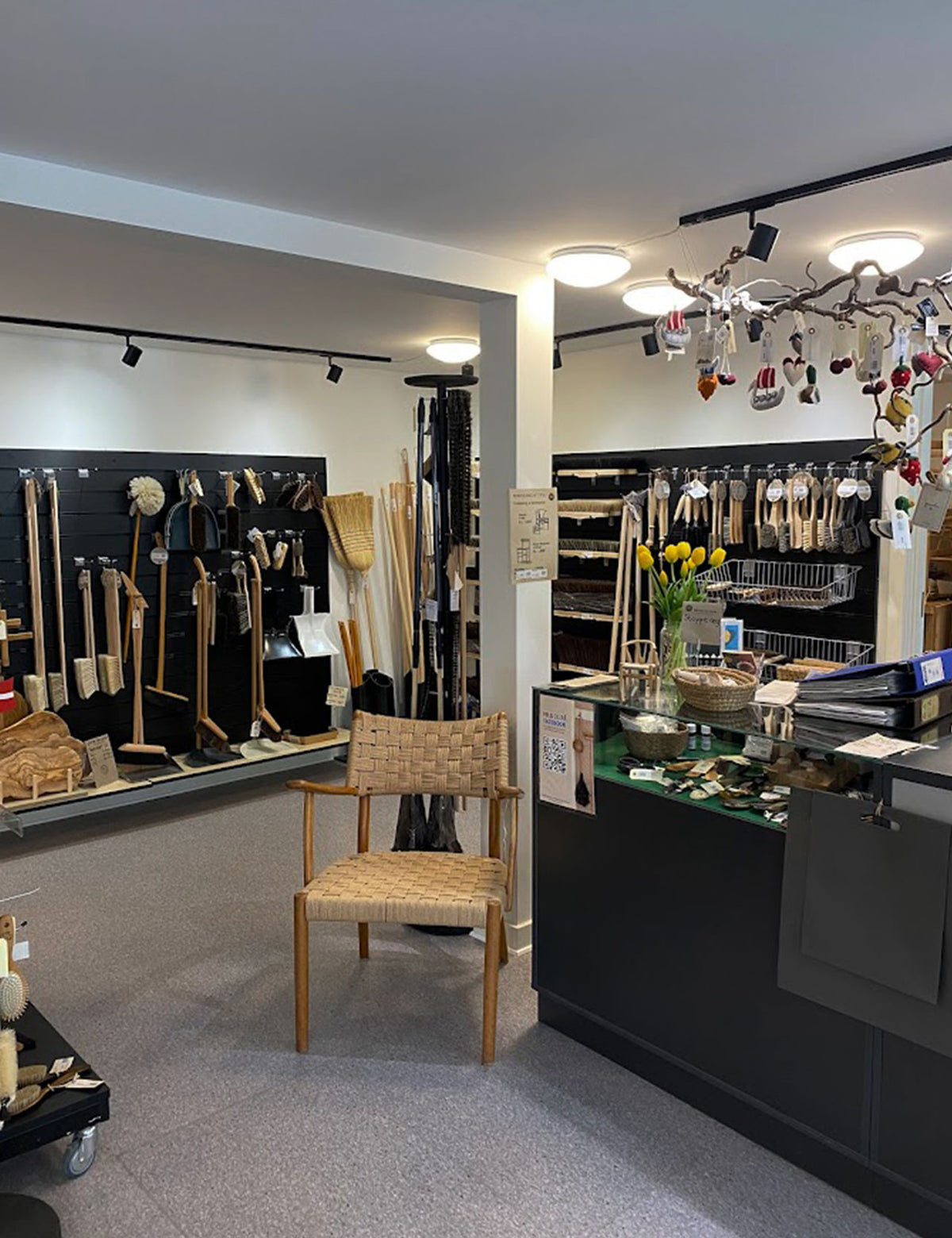 Butikken set fra siden med børster på væggene, disk og en flettet stol foran